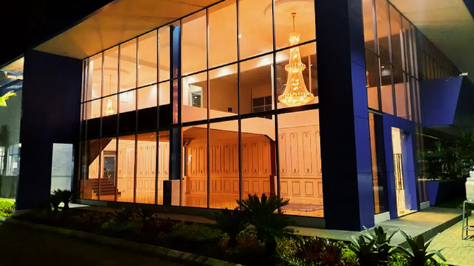 The glass lobby of the PT Daux Cosmetic building lit at night